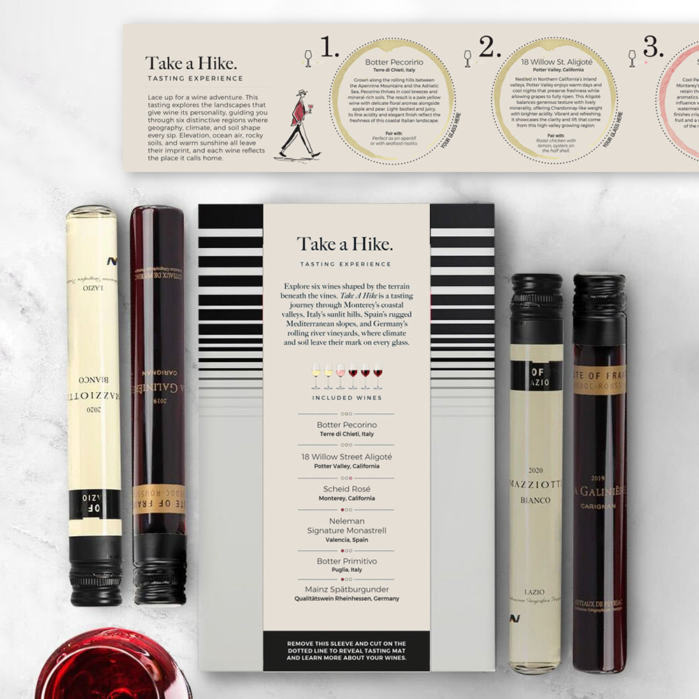 Boxed "Take a Hike" wine tasting kit with four slender wine tubes beside a striped tasting sleeve and informational card