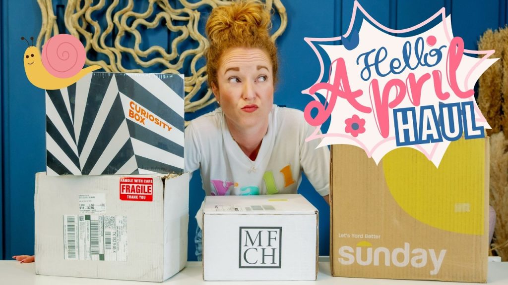 Redheaded woman with bun leaning over four subscription boxes (Curiosity, MFCH, Sunday), playful puzzled expression