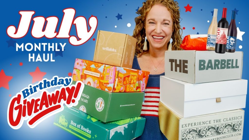 Alt_text: Person smiling while holding several stacked boxes with colorful designs, featuring text that reads "July Monthly H